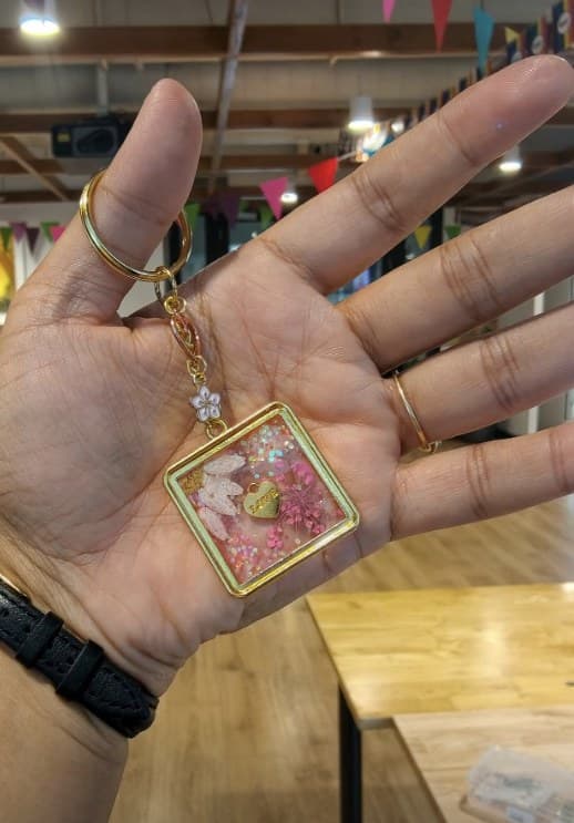 Pressed-flower resin pendant held in a palm