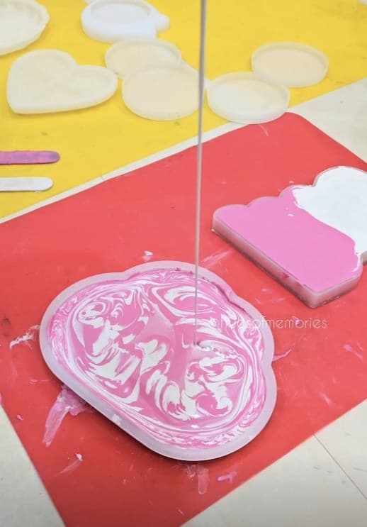 Pink and white resin being poured into a tray mould